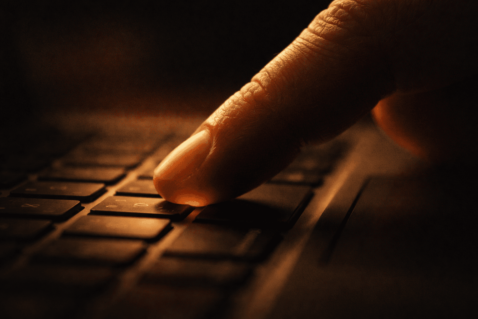 指がしびれた状態でキーボードの一キーを押そうとしている指先のクローズアップ。AI出版継続のイメージ。